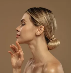 Mulher de perfil com o cabelo preso, orelha em evidência